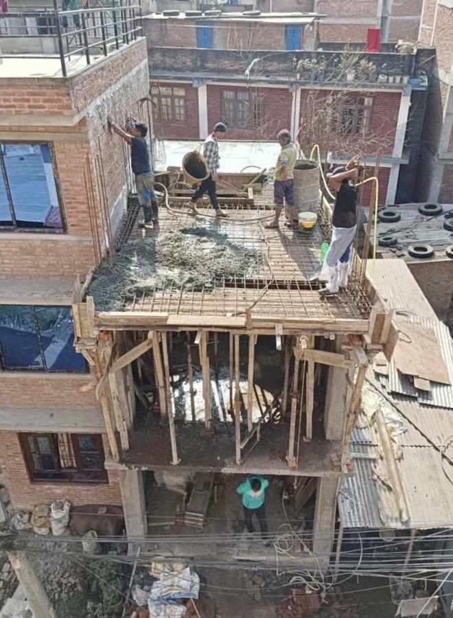 Workers pouring a concrete roof on a brick house