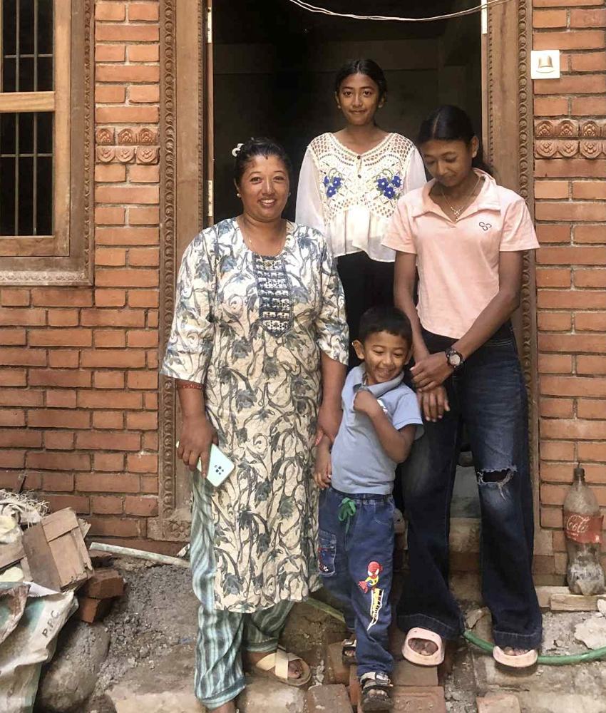 A mother and her children in the doorway of their new brick home