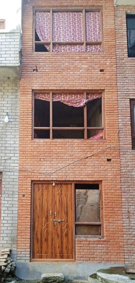 A narrow finished brick house with wooden doors