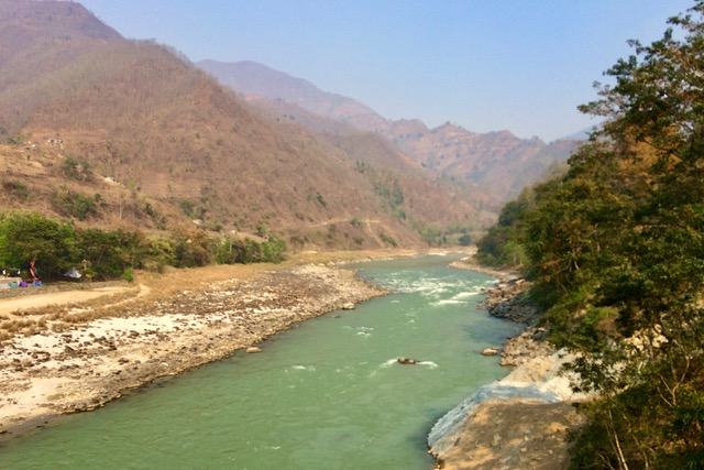 A green river winding between dry mountains in Nepal