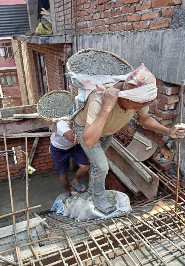 A worker carrying a basket of concrete